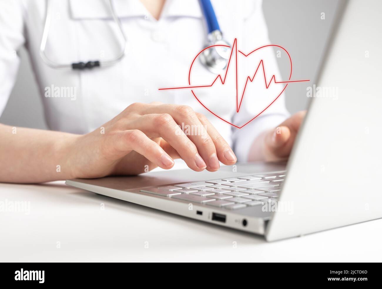 Medico che usa il computer portatile e che guarda il test elettrocardiografico, verificando la presenza di segni di malattie cardiache. Il cardiologo invia i risultati e le raccomandazioni ECG al paziente tramite Internet. Foto di alta qualità Foto Stock