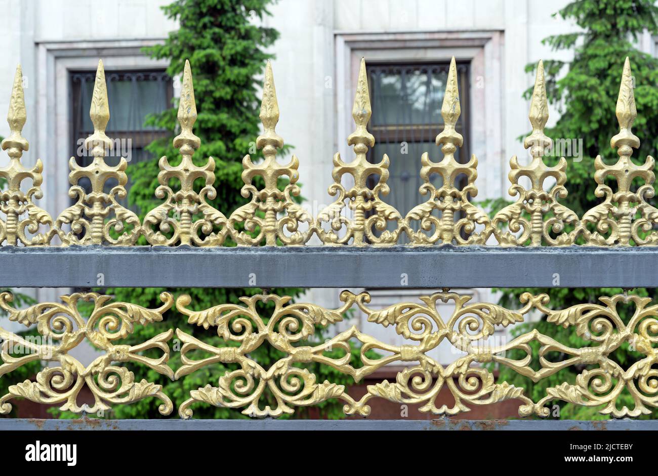 Elemento di una vecchia recinzione forgiata a punta con design nero e oro. Foto Stock
