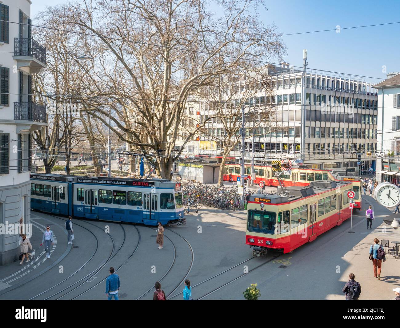Zurigo, Svizzera - Marzo 26th 2022: Vista sulla vivace piazza con tram di fronte alla stazione ferroviaria di Stadelhofen Foto Stock