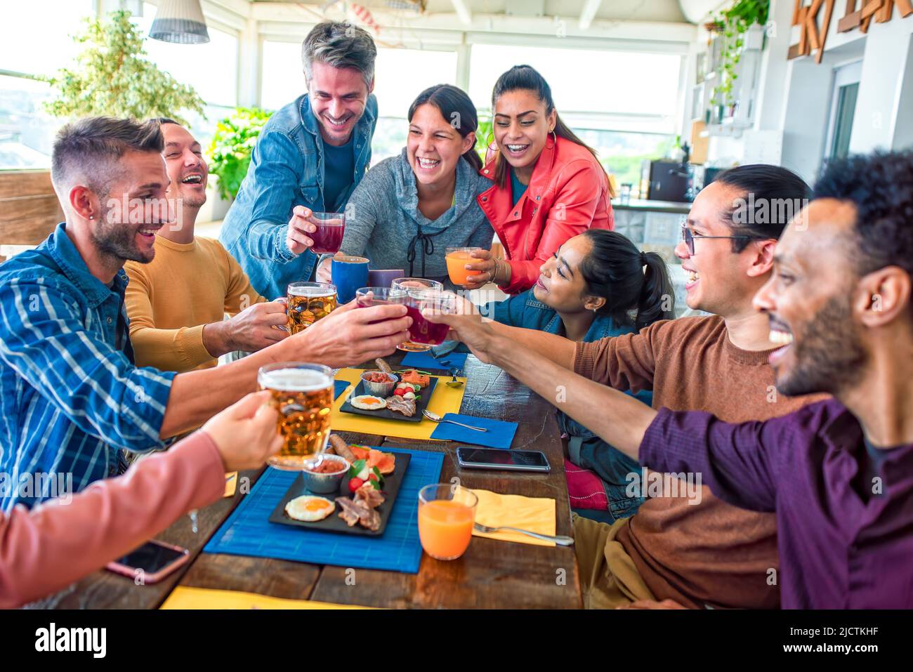 multietnico grande gruppo di amici seduti a tavola in un bar ristorante per il brunch. persone diverse sedano insieme la colazione salata gustando Foto Stock