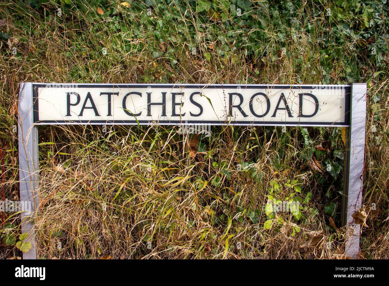 Patches Road nome strada segno su due posti con erbacce in background Foto Stock