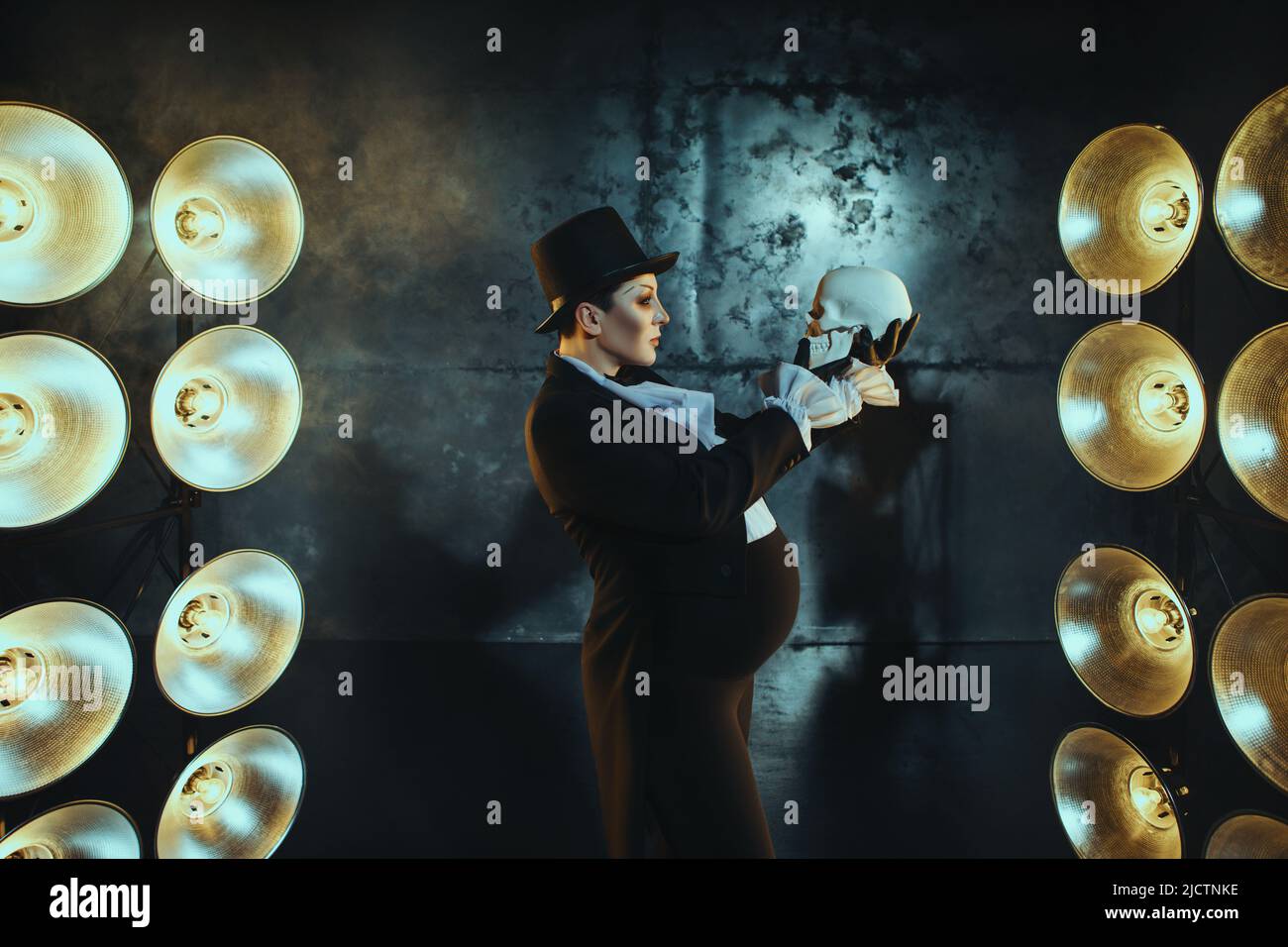 Ragazza incinta nell'immagine di un uomo grasso sullo sfondo di lampade al buio Foto Stock