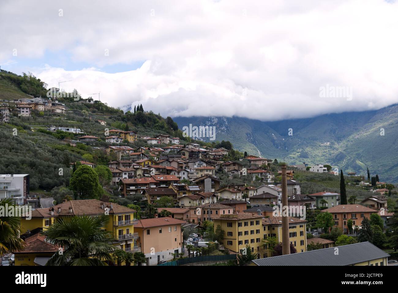 Italia: Panorama di un paese sul Lago di Garda con le cime delle Alpi coperte da nuvole Foto Stock