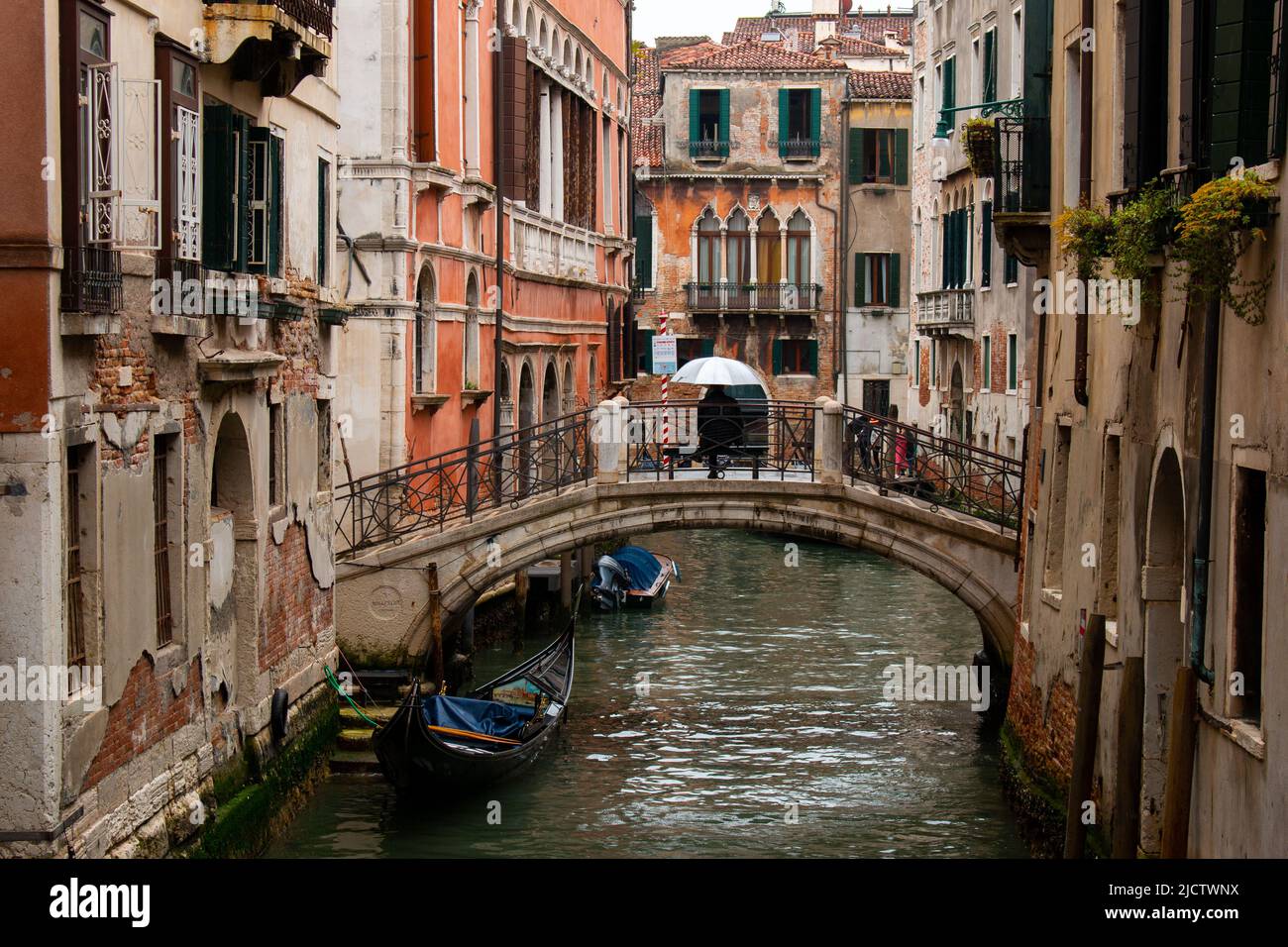 Una figura solitaria di un gondoliere sotto un enorme ombrello su un ponte vuoto in una mattina piovosa, Venezia, Italia Foto Stock