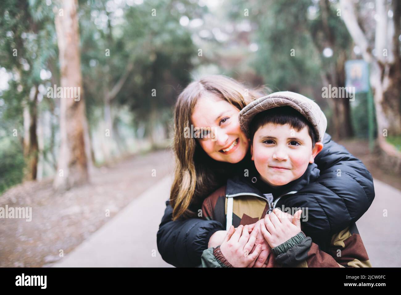 Madre single abbraccia il suo figlio giovane nel parco. Famiglia con un solo genitore Foto Stock
