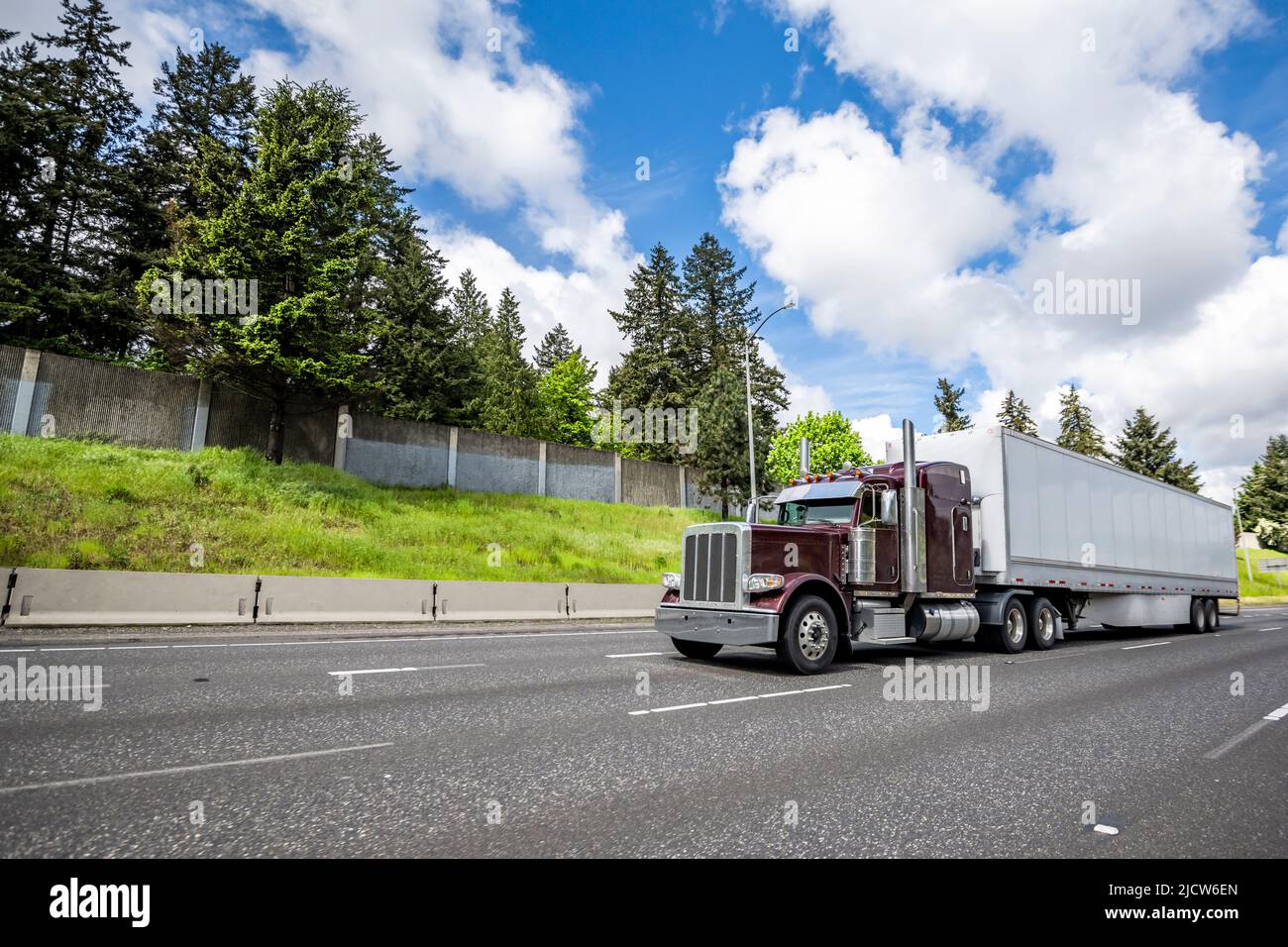 Carico classico carro grande borgogna trattore semirimorchio trasporto di carico commerciale in furgone a secco semirimorchio che corre sulla strada larga strada rettilinea a Foto Stock