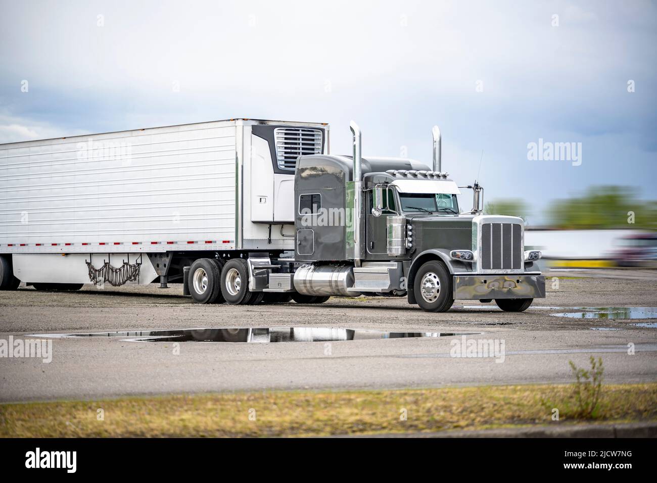 Trattore semi-camion industriale grigio a lunga percorrenza con cofano da carro grande classico e parti cromate e semirimorchio refrigerato in piedi per il resto del settore Foto Stock