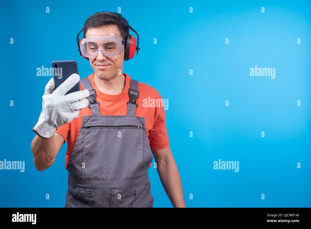 Artigiano positivo in uniforme messaggio di lettura su smartphone Foto Stock
