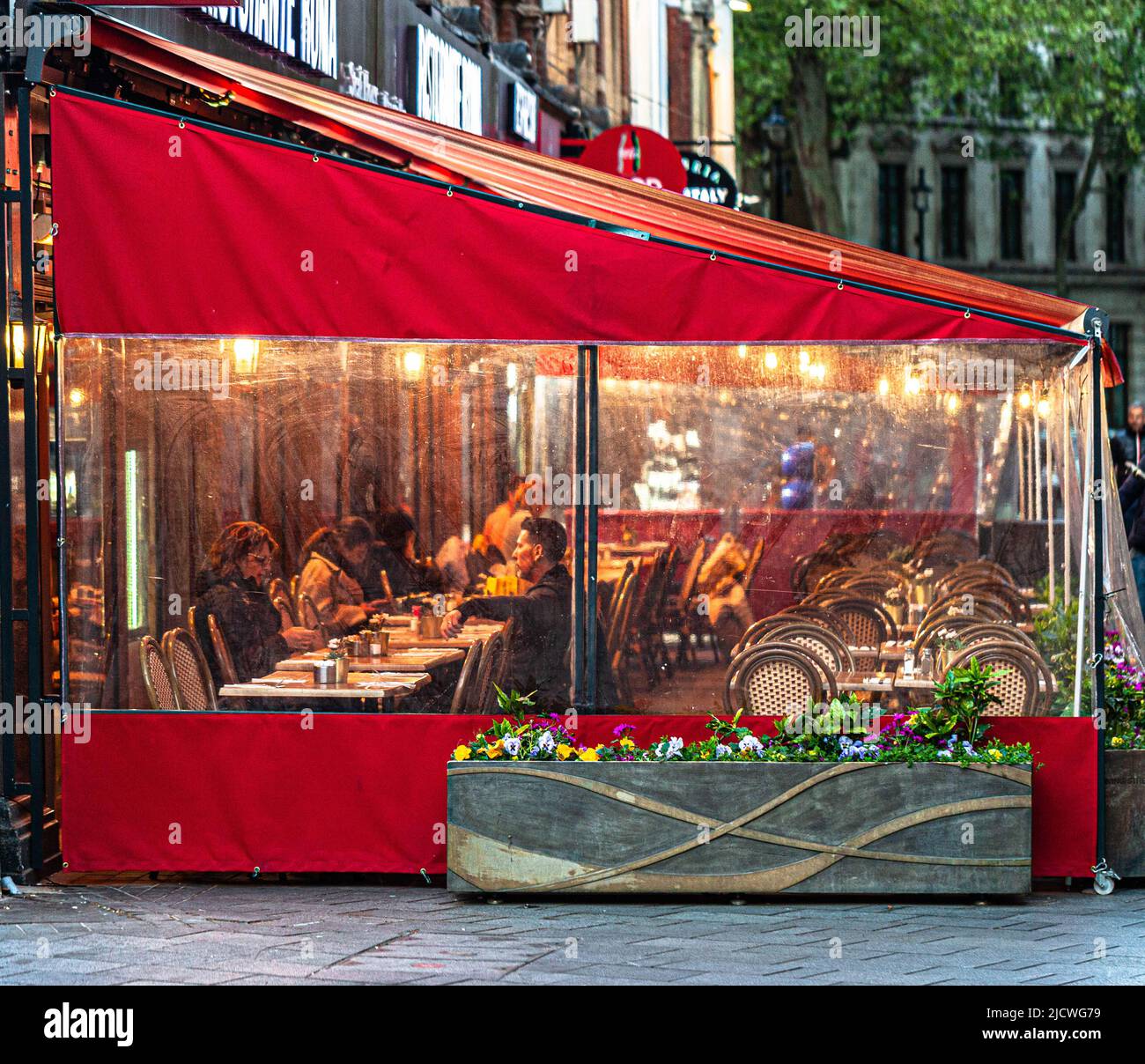 Clienti del ristorante seduti in terrazza sotto tenda in serata piovosa, Londra, Inghilterra, Regno Unito. Foto Stock