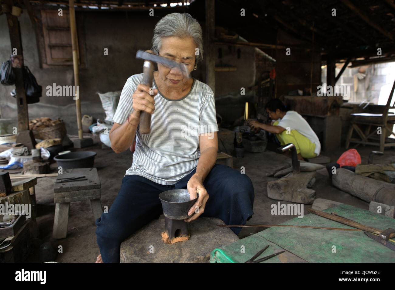 Una donna anziana che sta creando un argenteria in un laboratorio d'argento nel villaggio di Kamasan a Klungkung, Bali, Indonesia. Foto Stock