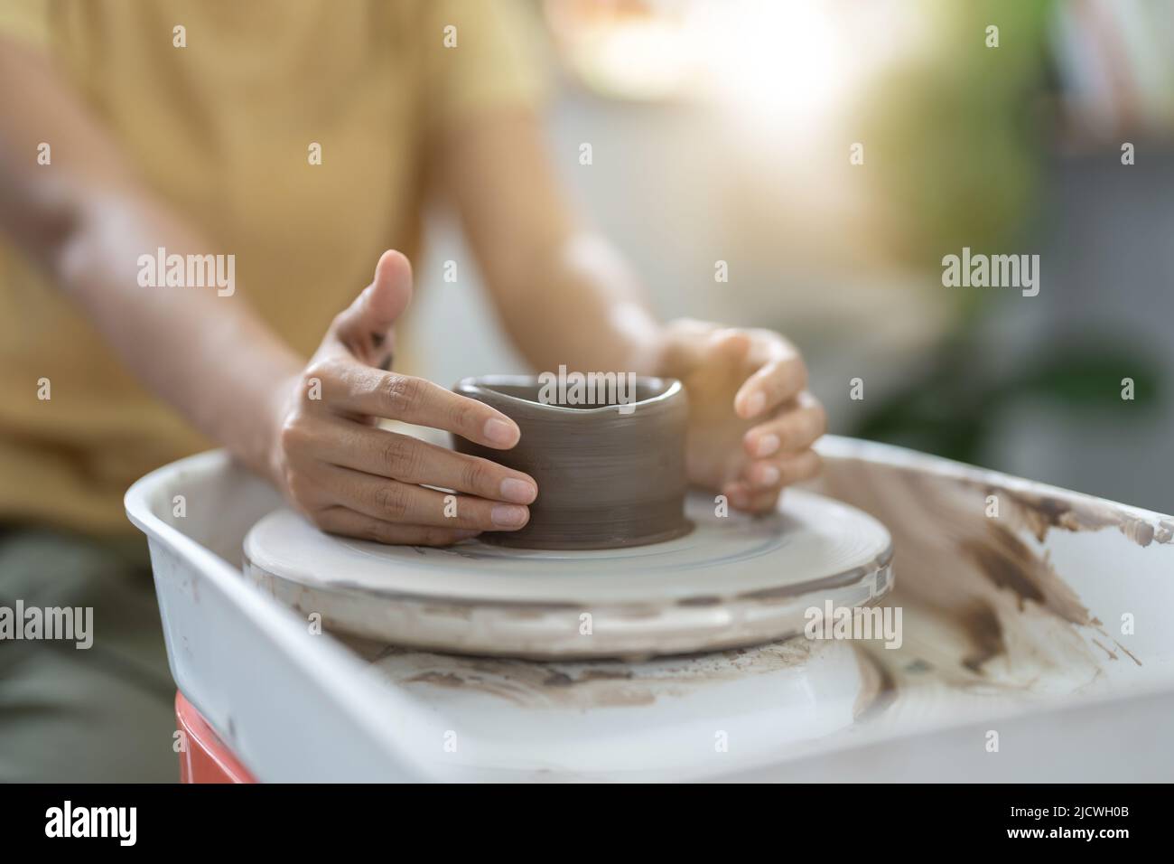 Mani artigiane che fanno ciotola di ceramica. Donna che lavora sulla ruota del vasaio. Il negozio per famiglie sculpts vaso da argilla. Foto Stock