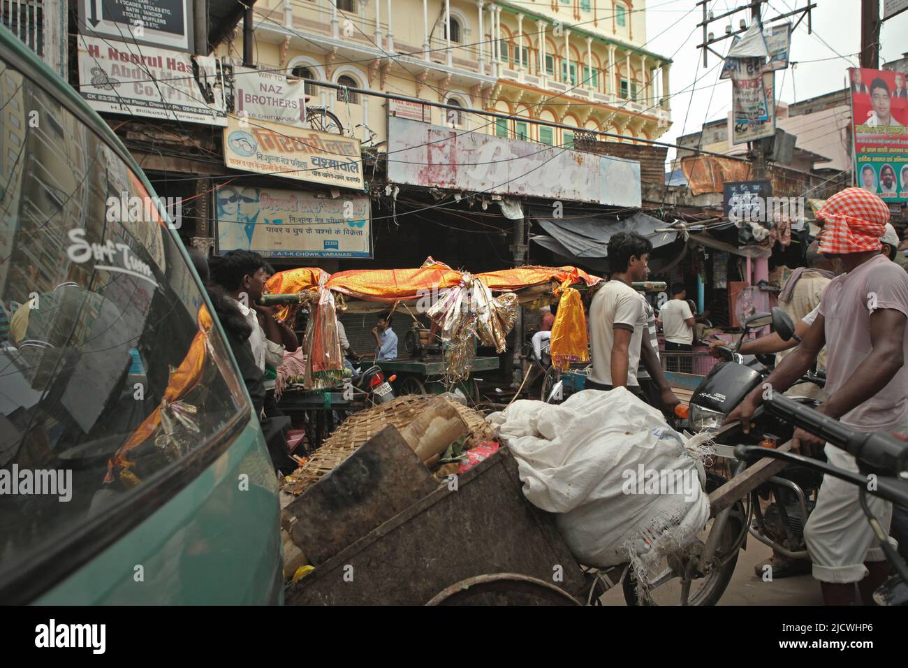 Gli uomini che trasportano un corpo mentre stanno camminando su una strada trafficata, dirigendosi verso uno dei ghat di cremazione sulla riva del fiume Ganges per la cremazione funeraria in Varanasi, Utar Pradesh, India. Foto Stock