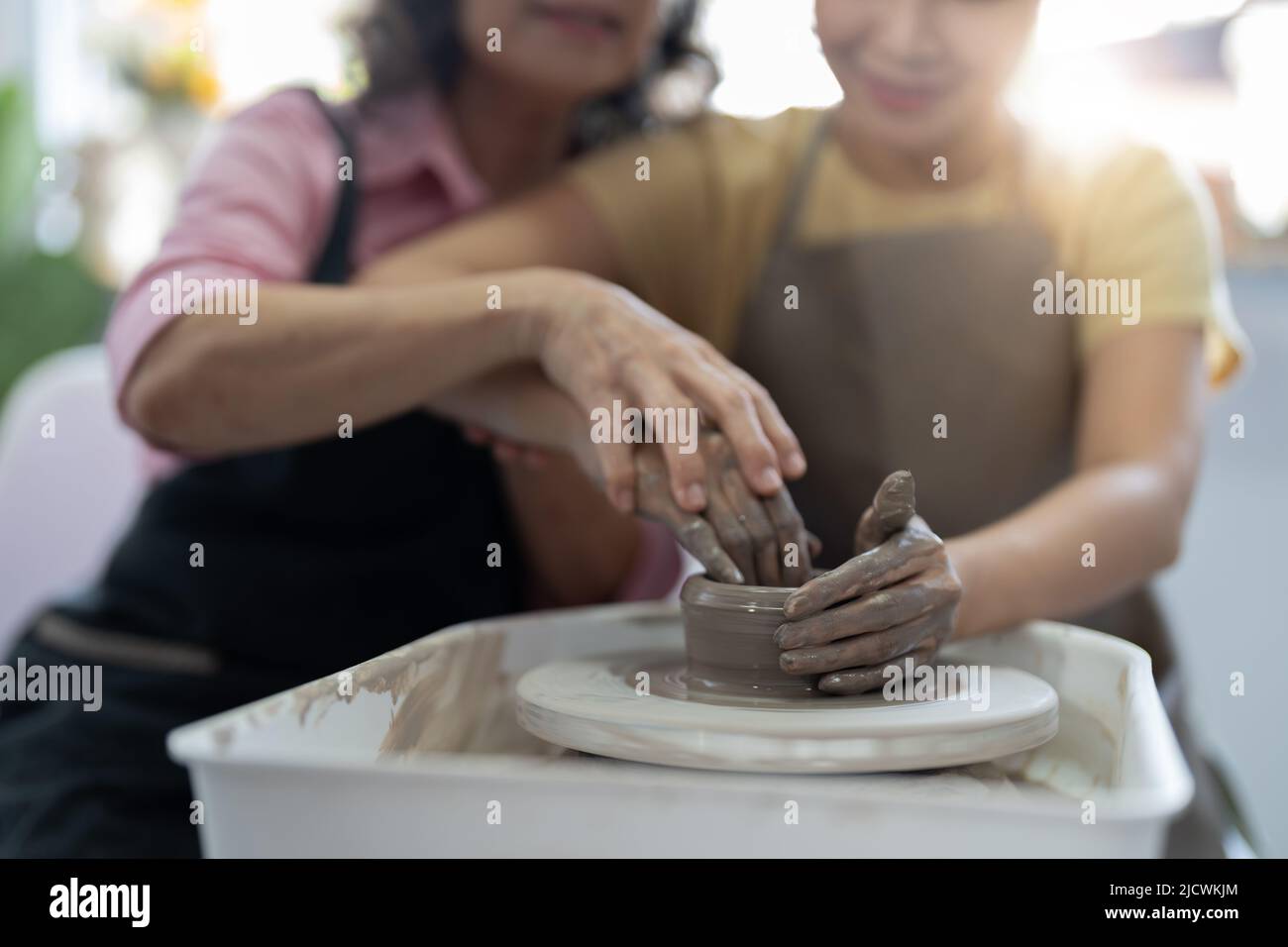 Laboratorio di ceramica. Senior insegna ceramica giovane donna asiatica. Modellazione di argilla Foto Stock