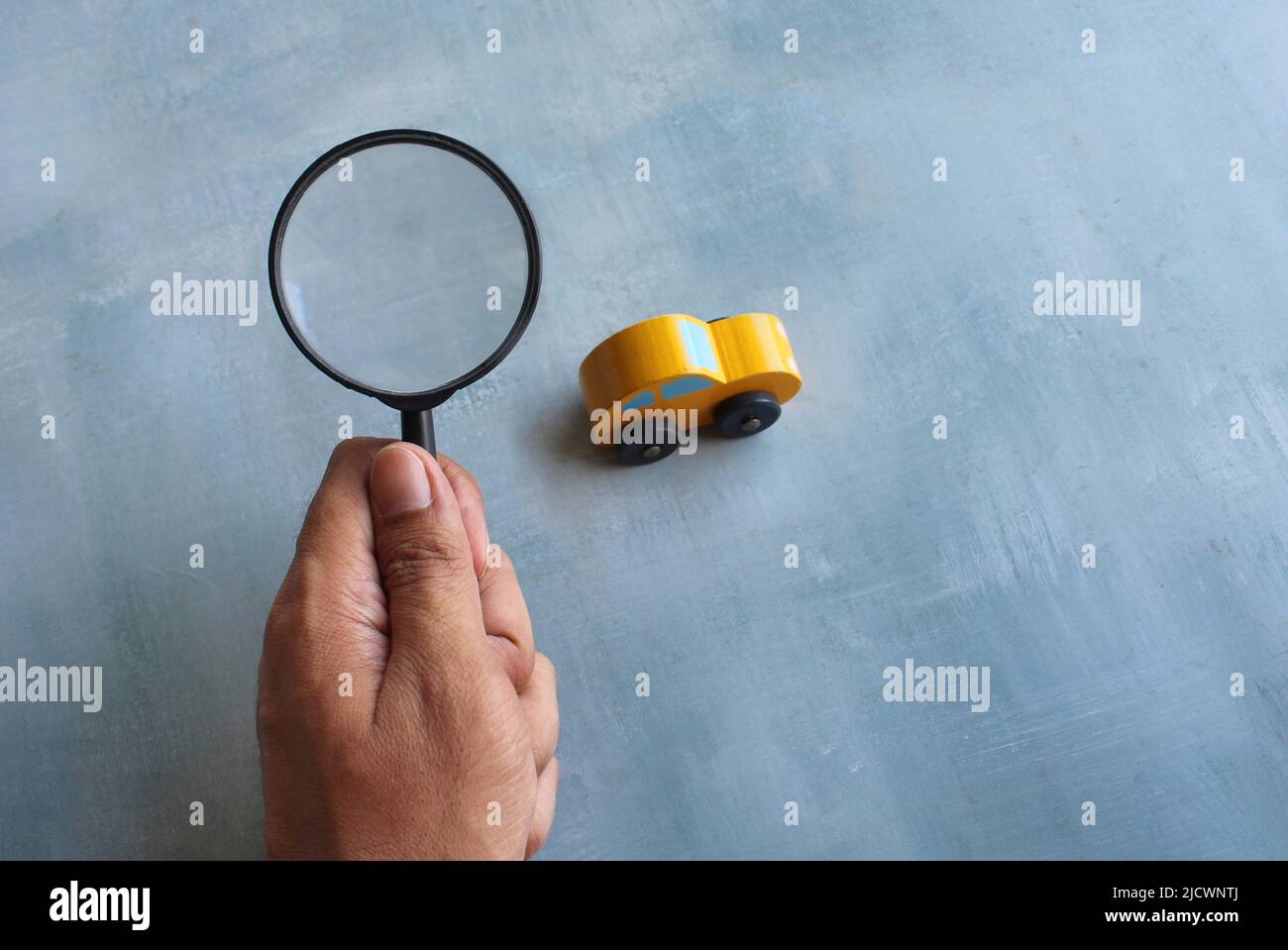 Lente d'ingrandimento e auto giocattolo. Ispezione dell'auto, ricerca, ricerca del concetto di auto. Foto Stock