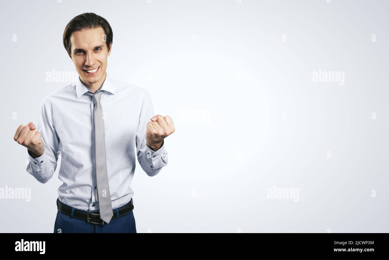 Concetto di successo di impresa e di vincita con giovane uomo gioioso su sfondo bianco della parete con copyspace per il vostro logo o testo, mock up Foto Stock