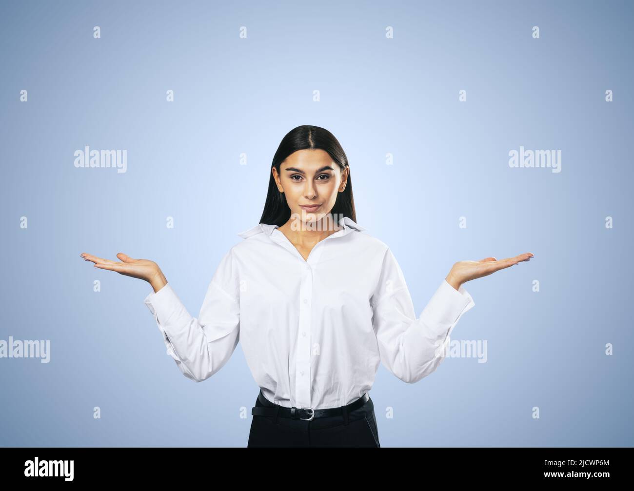 Concetto di scelta giusta con vista frontale su donna giovane confuso in camicia bianca isolato su sfondo astratto luce blu parete, primo piano Foto Stock