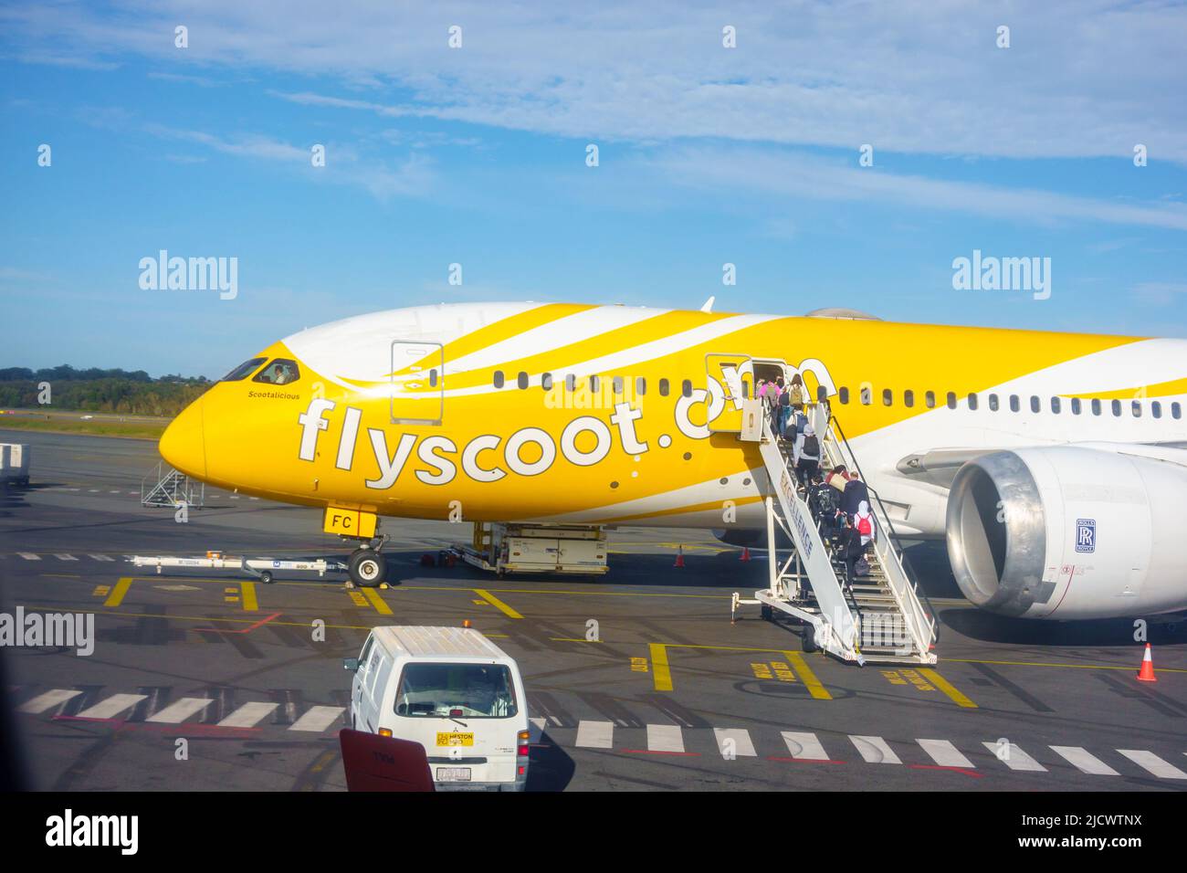 Coolangatta - Australia - Giugno 13 2022; volo aereo Flyscoot in giallo chiaro all'aeroporto mentre il passeggero si imbarca con l'equipaggio alla porta in cima alle imbarco Foto Stock