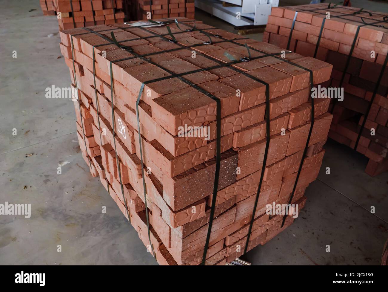 Mattoni rossi da costruzione accatastati su un magazzino all'aperto. Materiale consegnato dalla fabbrica. Mattone immagazzinato per costruzione di edificio Foto Stock