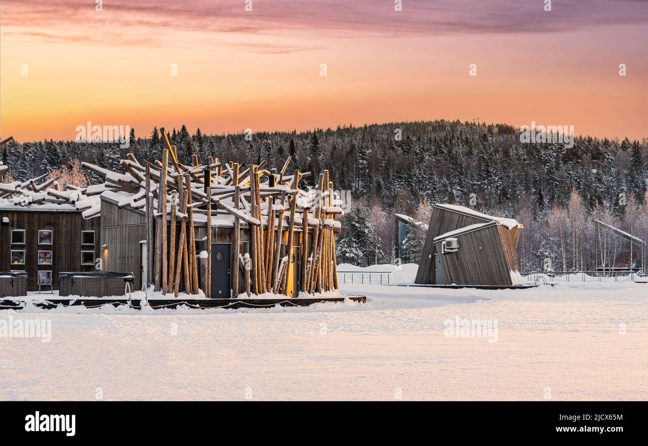 Cielo romantico all'alba sopra l'Arctic Bath Hotel e cabine galleggianti su fiume ghiacciato coperto di neve, Harads, Lapponia, Svezia, Scandinavia, Europa Foto Stock