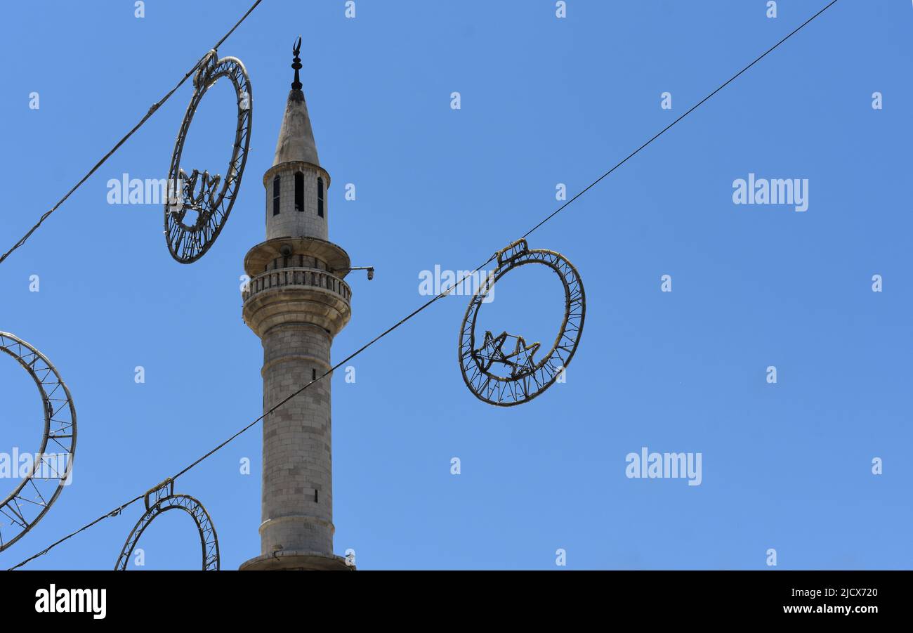 Decorazioni del Ramadan appese nella strada a Eid di fronte ad un minareto moschea a Madaba in Giordania Foto Stock