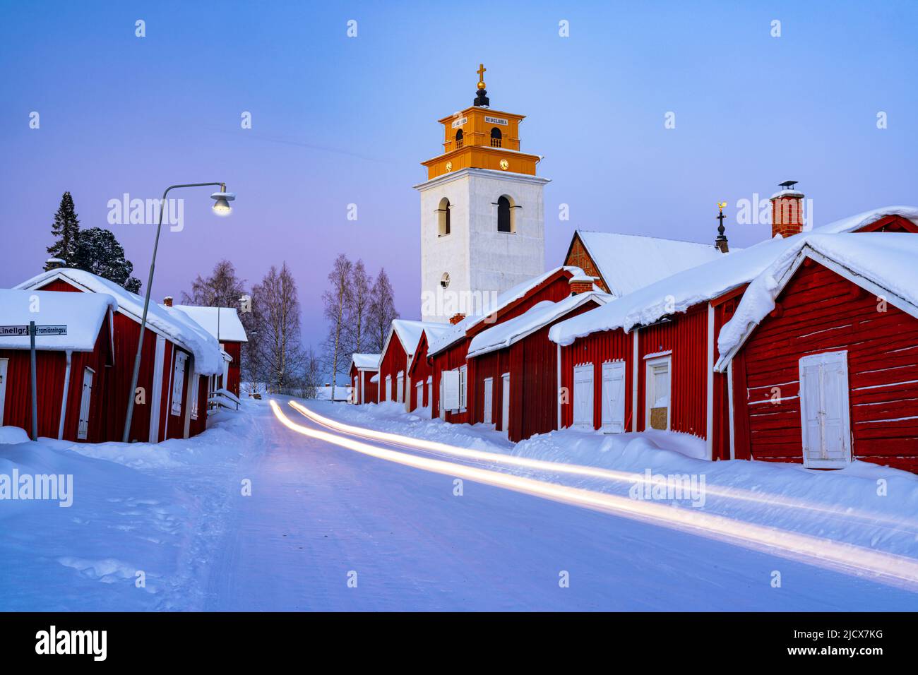 I percorsi automobilistici si illuminano sulla strada ghiacciata che attraversa la medievale città della chiesa di Gammelstad coperta di neve, patrimonio dell'umanità dell'UNESCO, Lulea, Svezia Foto Stock