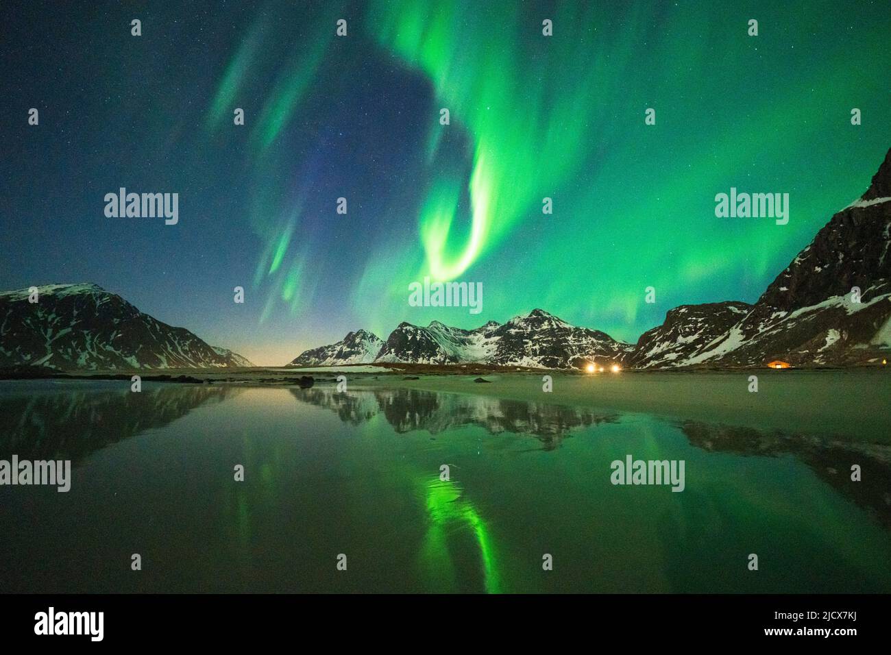Cielo notturno luminoso con Aurora Borealis (aurora boreale) sulle montagne e sulla spiaggia di Skagsanden, Flakstad, Isole Lofoten, Norvegia, Scandinavia, Europa Foto Stock