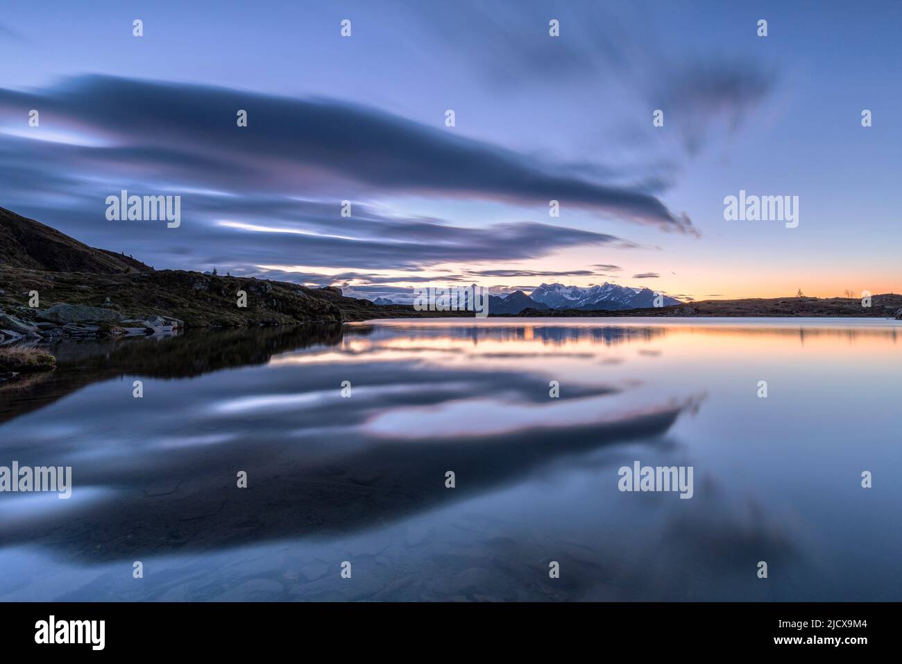 Nuvole folli che si riflettono nel lago di Arcoglio all'alba, in Valmalenco, Valtellina, Lombardia, Italia, Europa Foto Stock