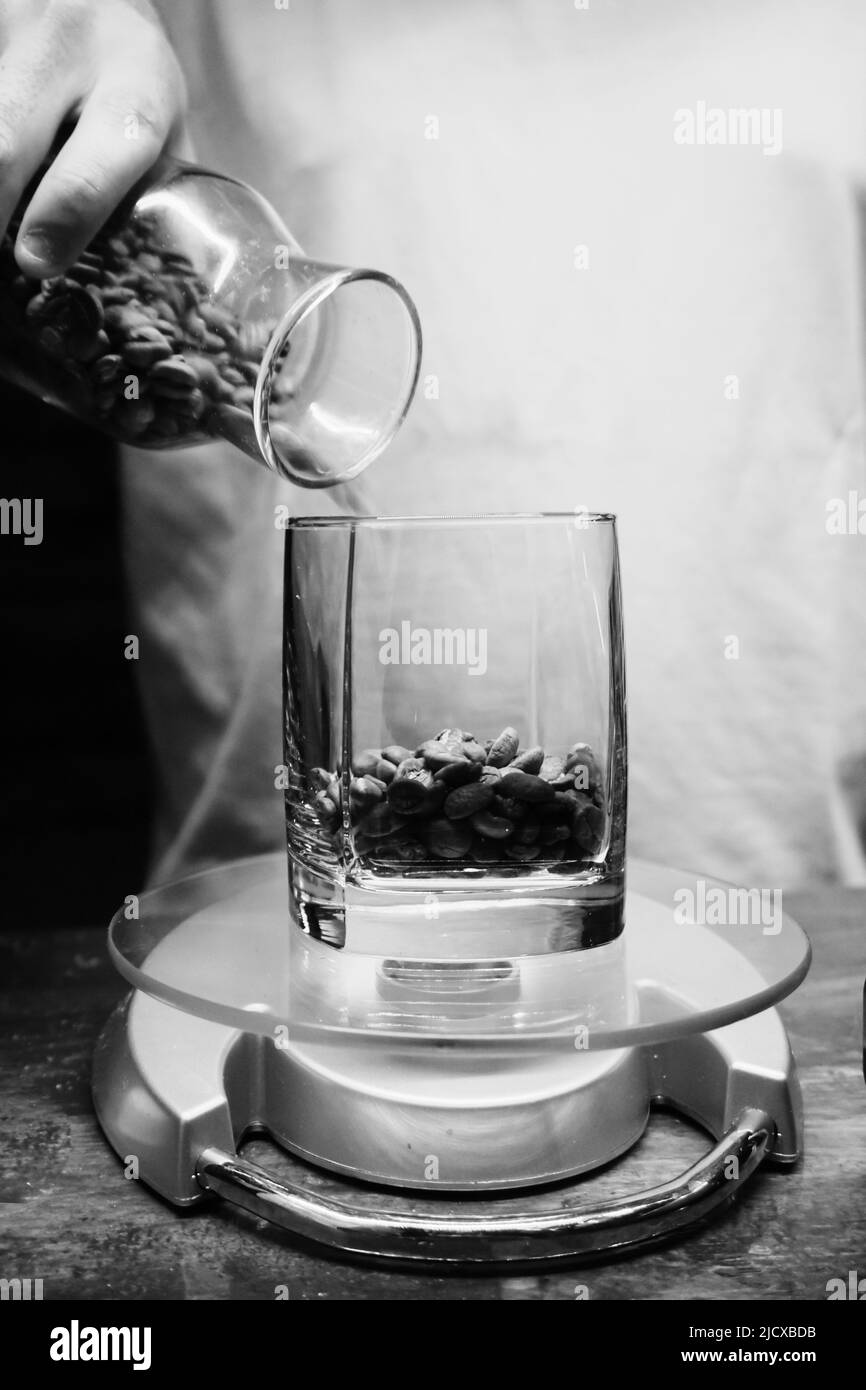 Il barista versa i chicchi di caffè freschi sulla bilancia da cucina vista ravvicinata Foto Stock