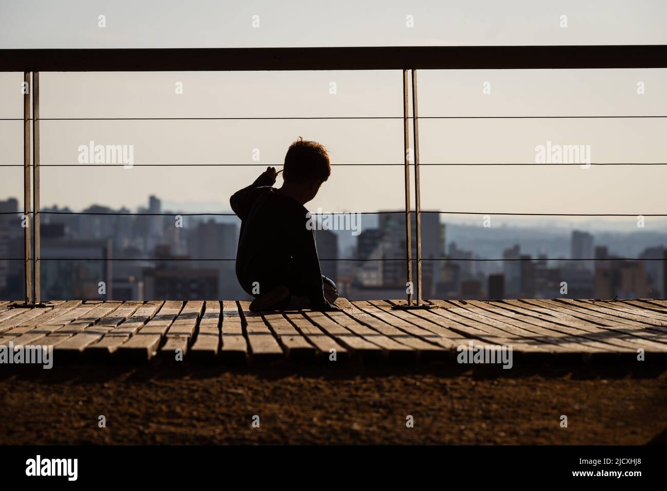 Vista posteriore di un ragazzo sul ponte di Parque Amilcar Vianna Martins guardando gli edifici alti in Belo Horizonte, Minas Gerais, Brasile. Foto Stock