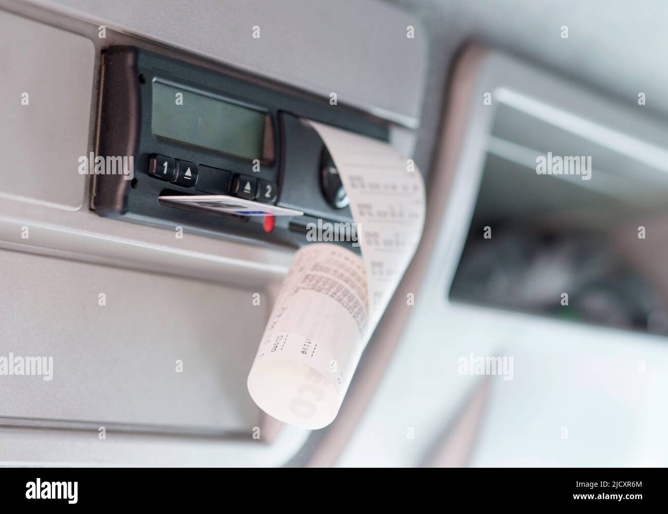 Primo piano di un tachigrafo digitale con una scheda del conducente espulsa e tempi di guida stampati. Fine del turno. Foto Stock