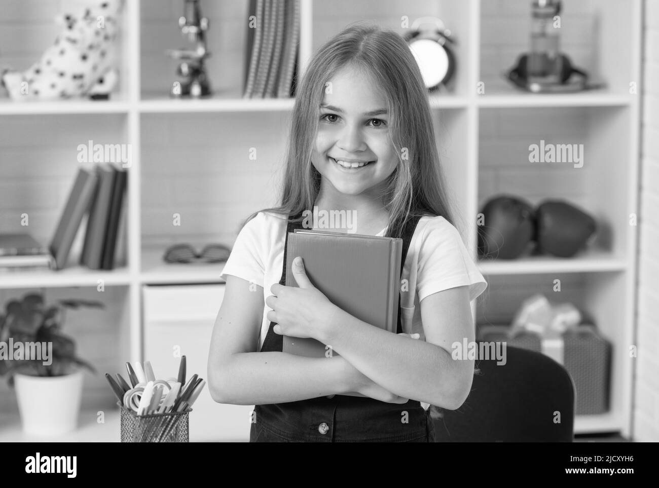 sorridente ragazza teen tenere notebook a scuola lezione in classe indossare uniforme, infanzia Foto Stock