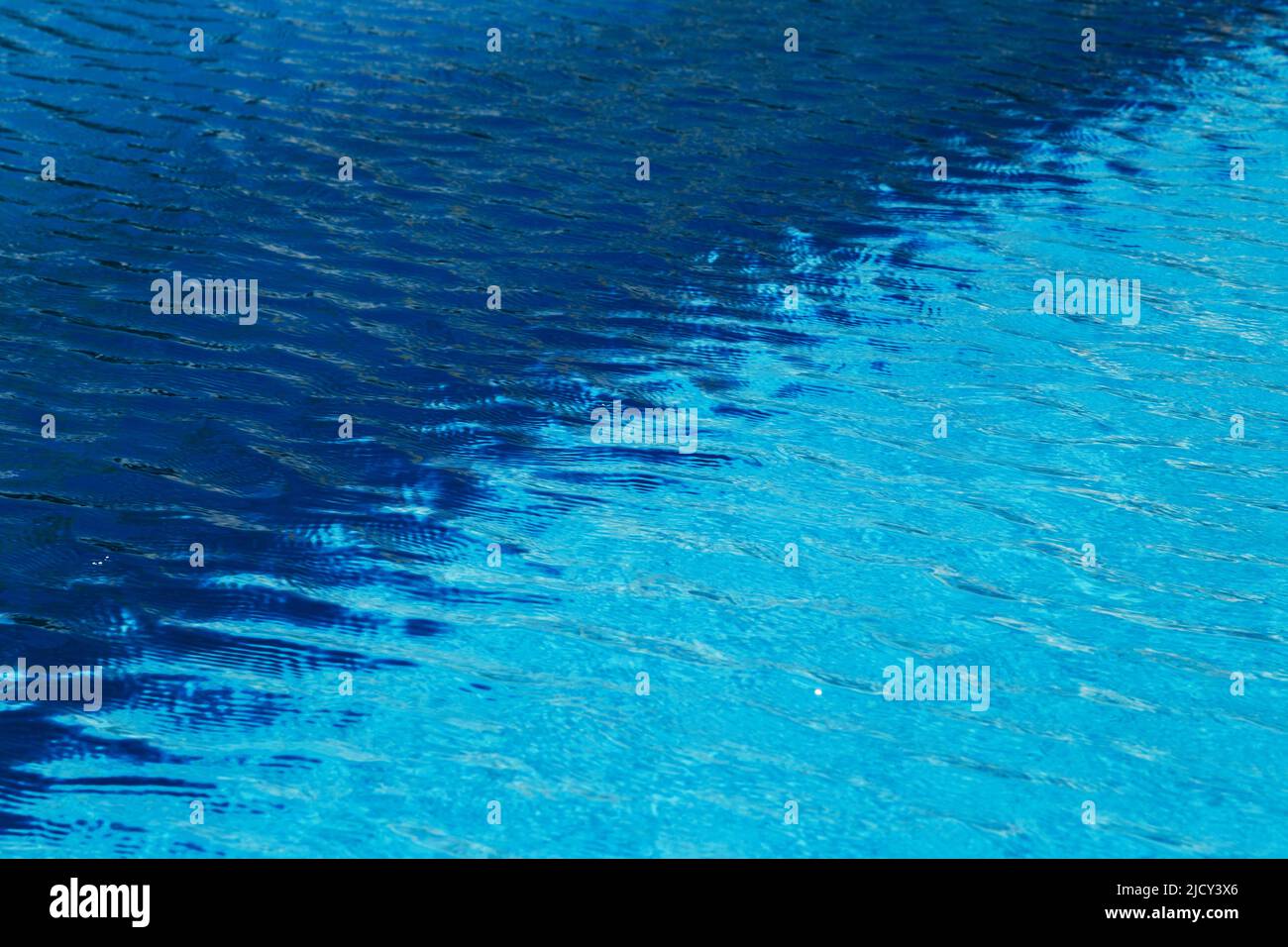 Due colori di acqua chiara e blu scuro con increspature e riflessi soleggiati in piscina Foto Stock