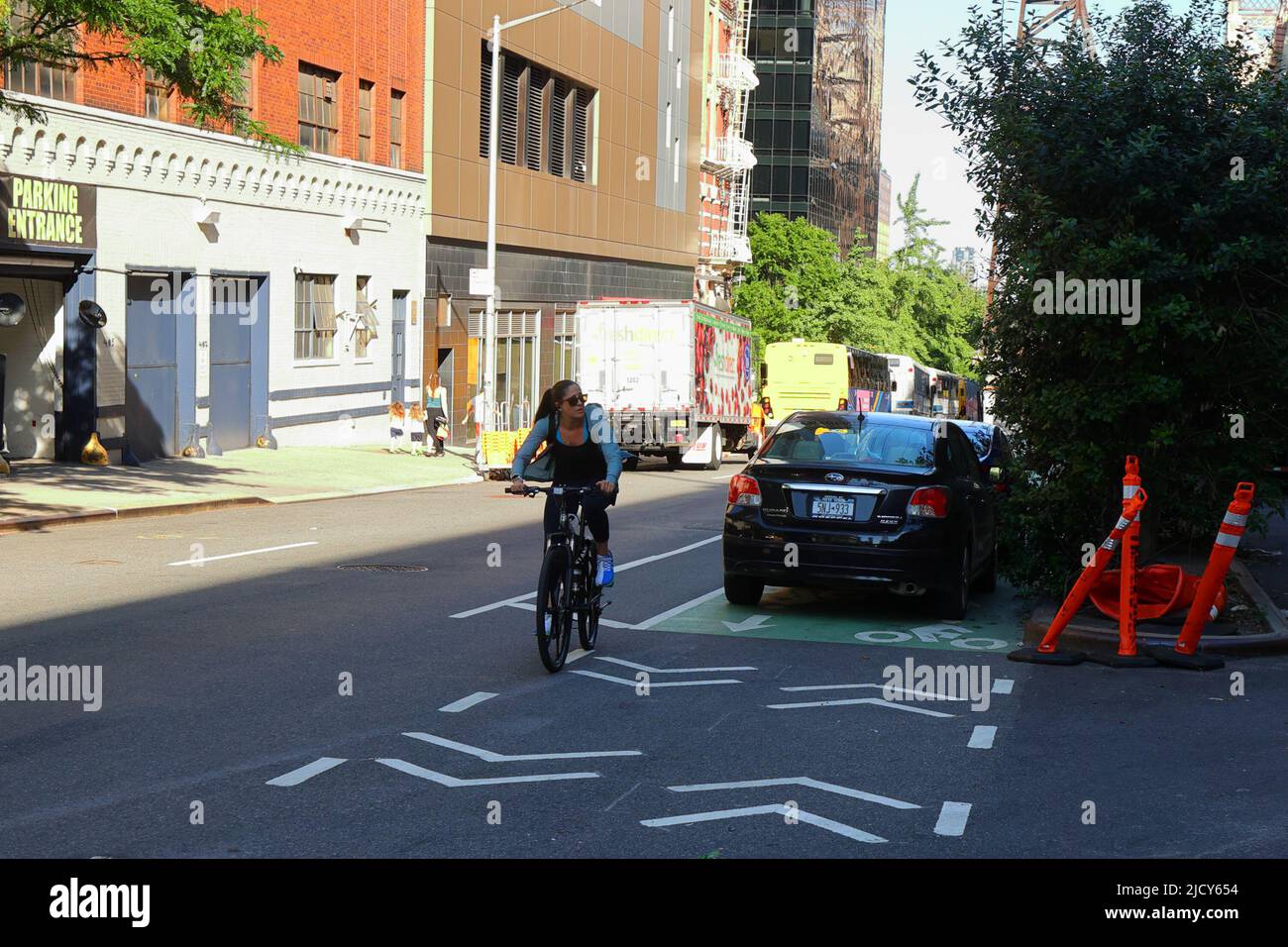 Un bicyclist manuevers intorno a parecchie automobili parcheggiate che bloccano una pista bidirezionali della bici a New York City. Foto Stock