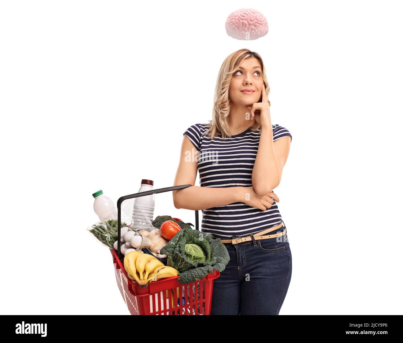 Giovane donna intelligente che tiene un cestino di shopping e cervello che galleggia sopra la sua testa isolato su sfondo bianco Foto Stock