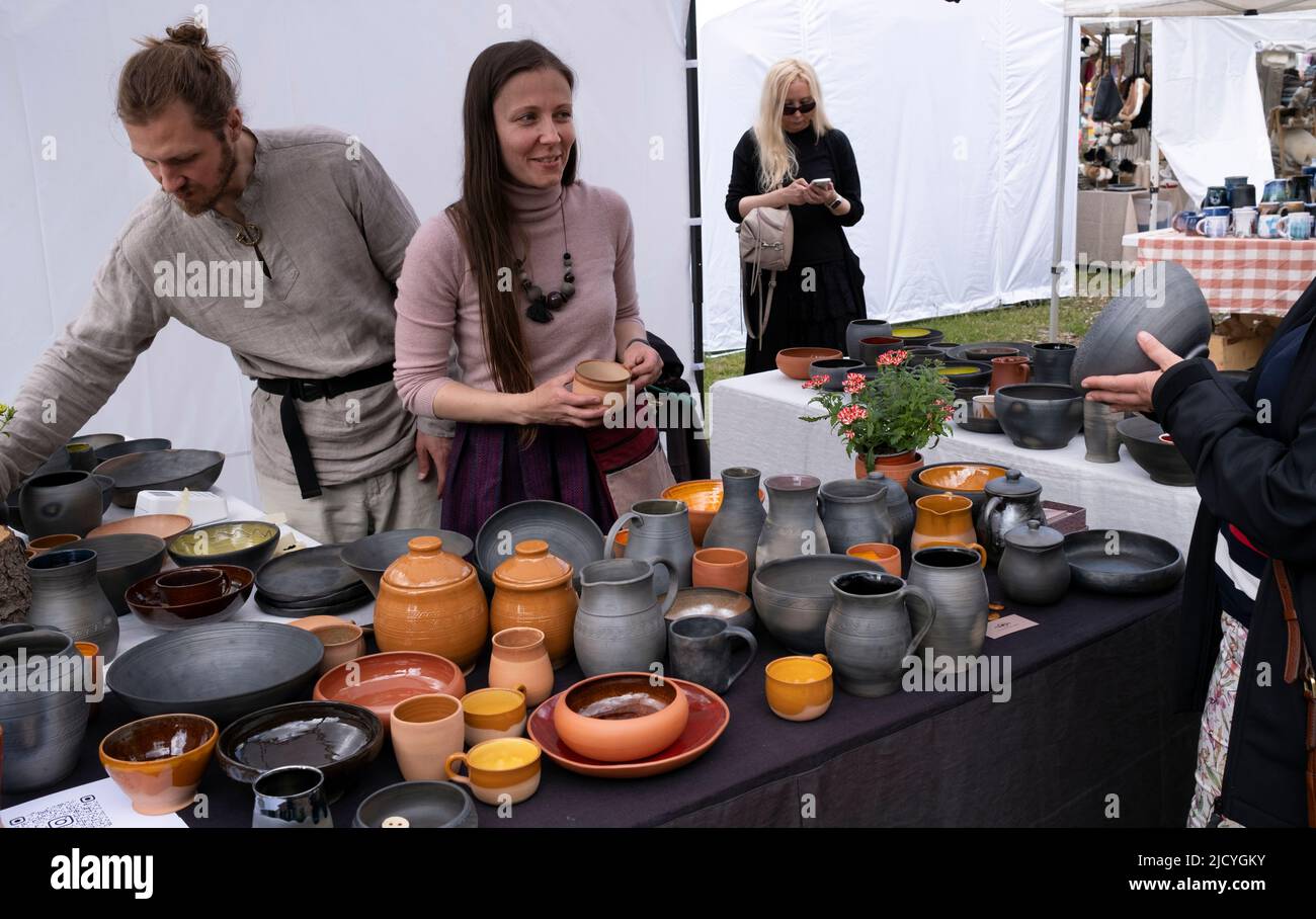 Donna che vende prodotti in ceramica al cliente presso il Museo Etnografico all'aperto della Lettonia Foto Stock