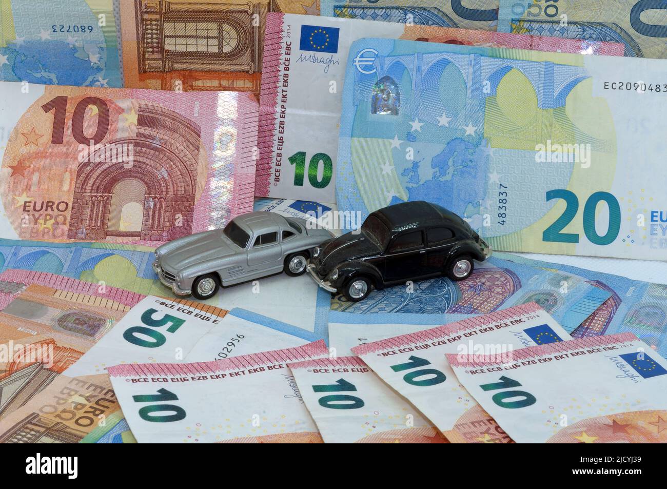 Immagine del simbolo: Costi, inflazione, auto su sfondo di banconote. Foto Stock