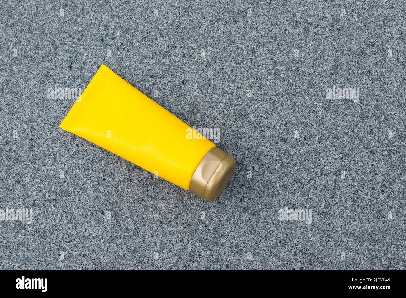 Tubo color crema giallo su sfondo grigio. Foto Stock