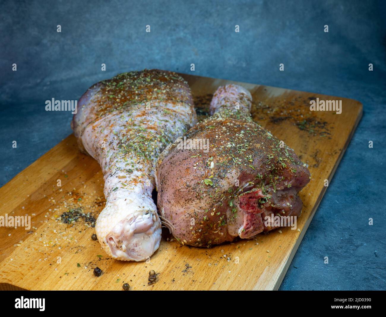 Bastoncini di tacchino in spezie giacciono su un tagliere da cucina. Carne di pollame. Gamba di tacchino. La carne succosa aspetta di essere cucinata. In attesa del forno. Uncook Foto Stock