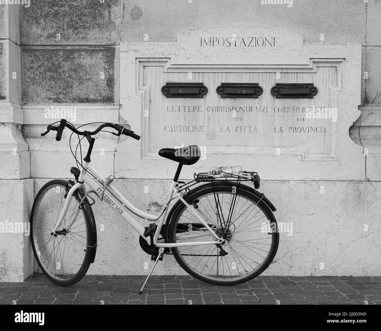 Mantova, Italia - 26 febbraio 2022 - una bicicletta in piedi vicino alla casella postale dell'Ufficio postale Centrale. Sulla parete di marmo, dall'alto verso il basso e da le Foto Stock