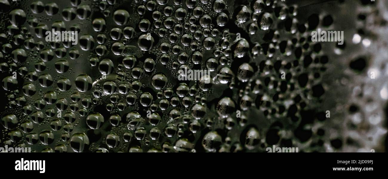 Molte gocce d'acqua pioggia bagnano la condensa del finestrino sul vetro. Sfondo fresco. Texture formate da bolle. Superficie trasparente di raccolta. Foto astratta reale Foto Stock