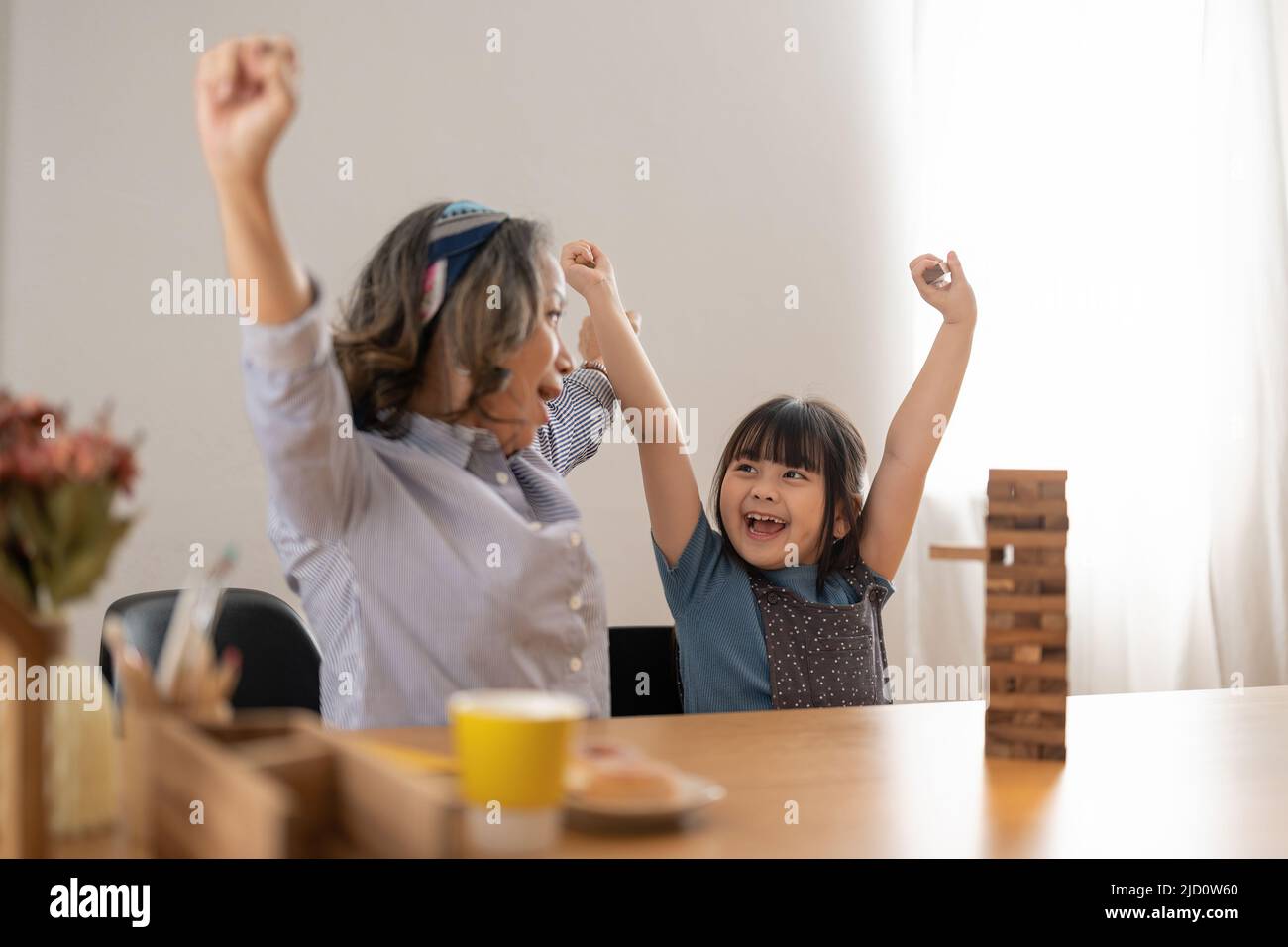 Momenti felici di nonna asiatica con sua nipote che gioca jenga costruttore. Attività ricreative per i bambini a casa. Foto Stock