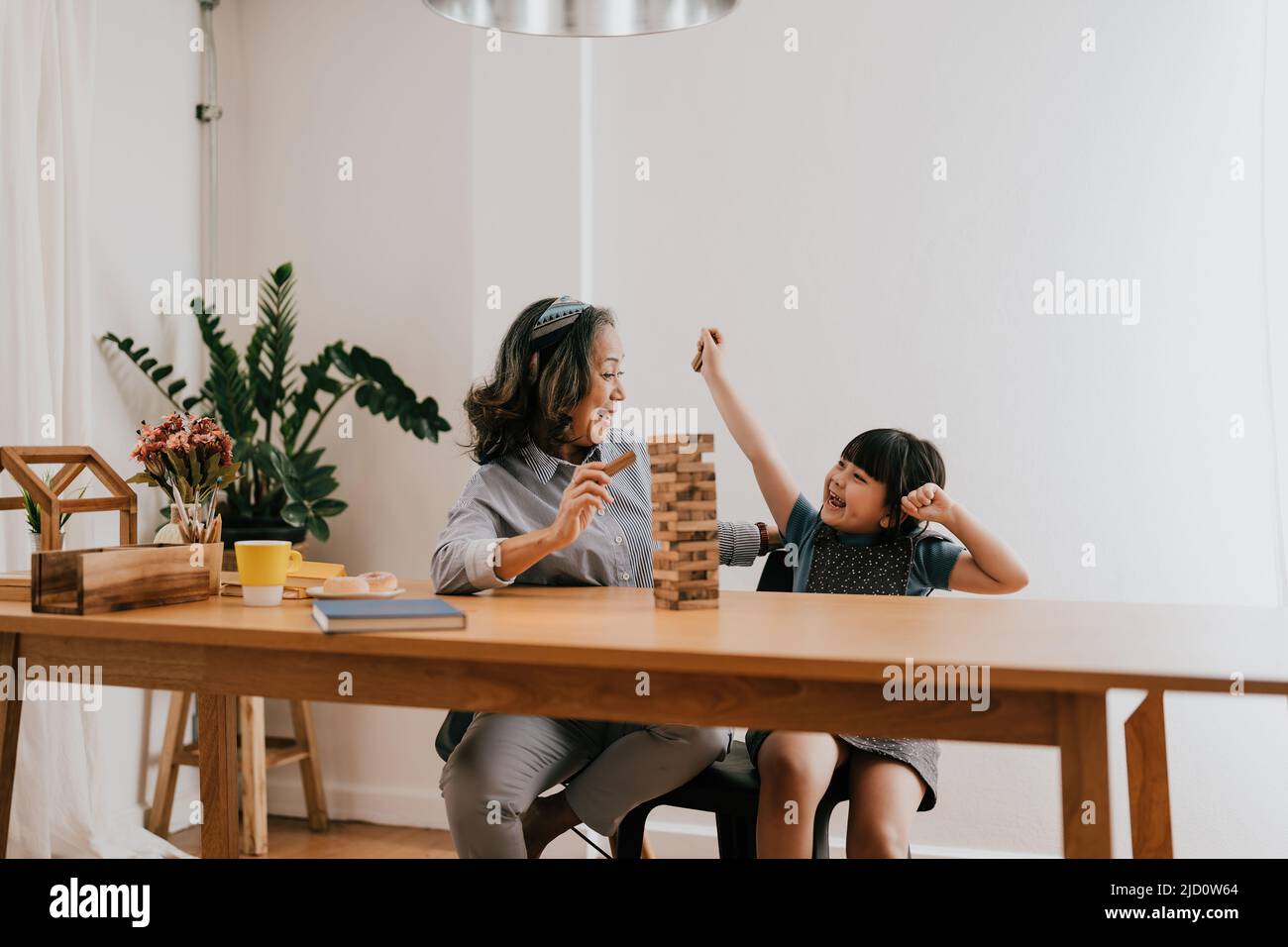 Momenti emozionanti felici della nonna asiatica con la sua nipote che gioca il costruttore di jenga. Attività ricreative per i bambini a casa. Foto Stock