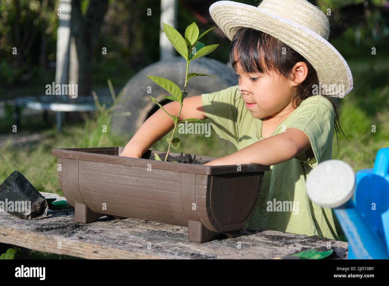 La bambina che indossa un cappello aiuta la madre nel giardino, un piccolo giardiniere. Cute ragazza piantando fiori in pentole per la vendita. Famiglia piccola impresa Foto Stock