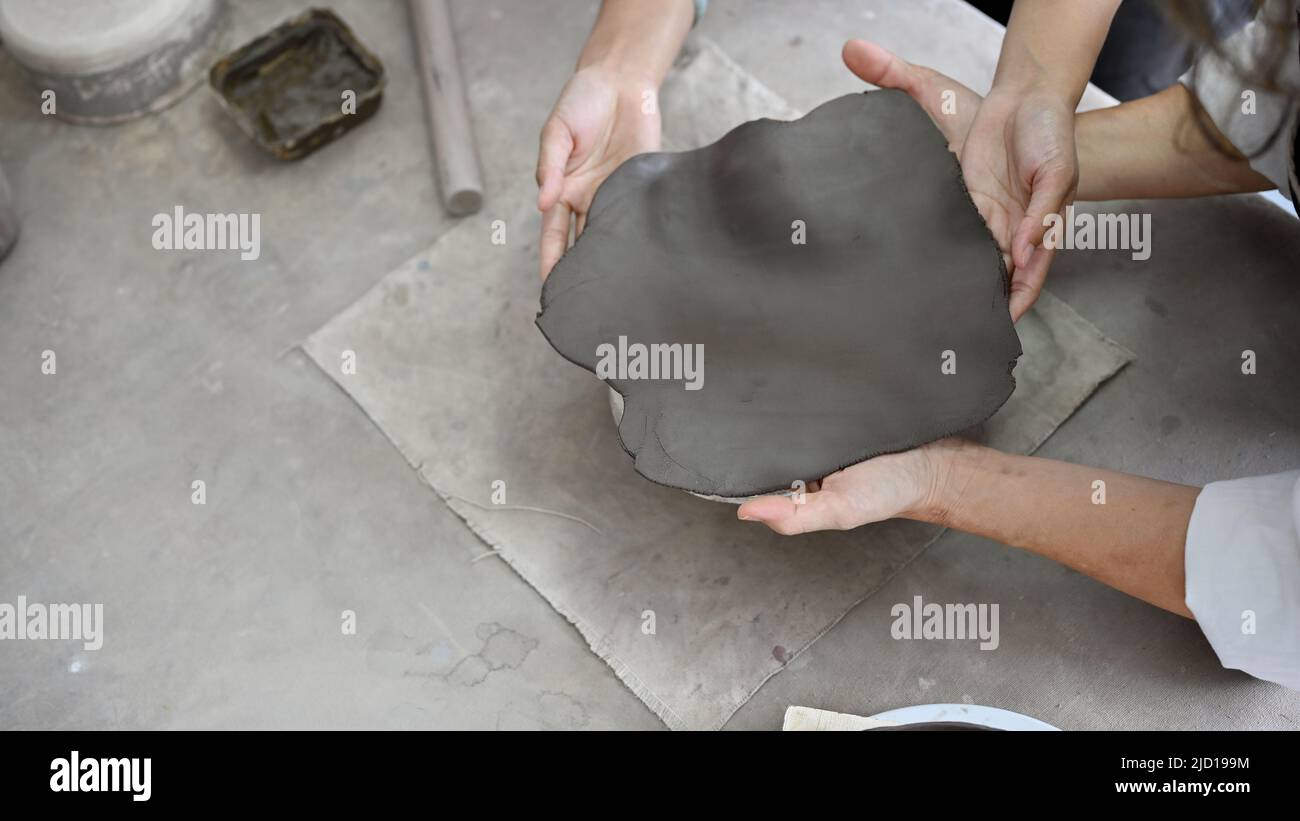 Vista dall'alto, due donne che fanno insieme una ceramica di argilla, stampando argilla con le mani. Concetto di workshop sulle attività creative. Foto Stock