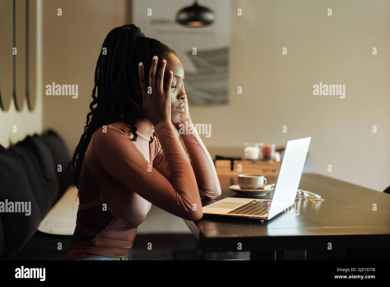 Donna americana multirazziale assonnata, studente che lavora online da un portatile al bar, ufficio creativo. Mal di testa, dolore, malessere Foto Stock