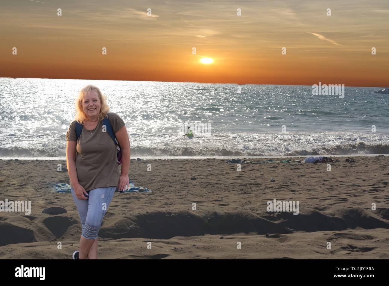 Mujer en ropa de senderismo - se encuentra en la playa al atardecer Foto Stock