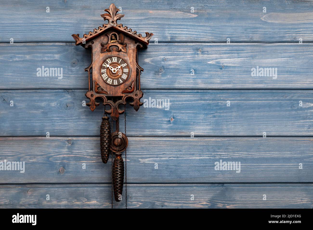 Antico orologio a cucù della Foresta Nera di fronte a una parete di legno blu, foto studio, Foresta Nera, Baden-Wuerttemberg, Germania Foto Stock