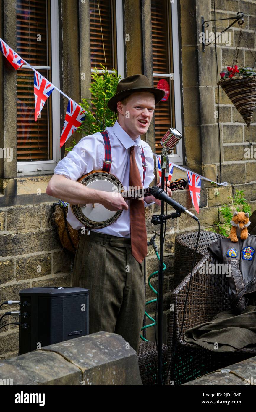 Evento di storia vivente di Haworth 1940 (artista solista, lettore di musica dal vivo, abbigliamento retrò, bunting, microfoni) - Main Street, West Yorkshire Inghilterra UK Foto Stock