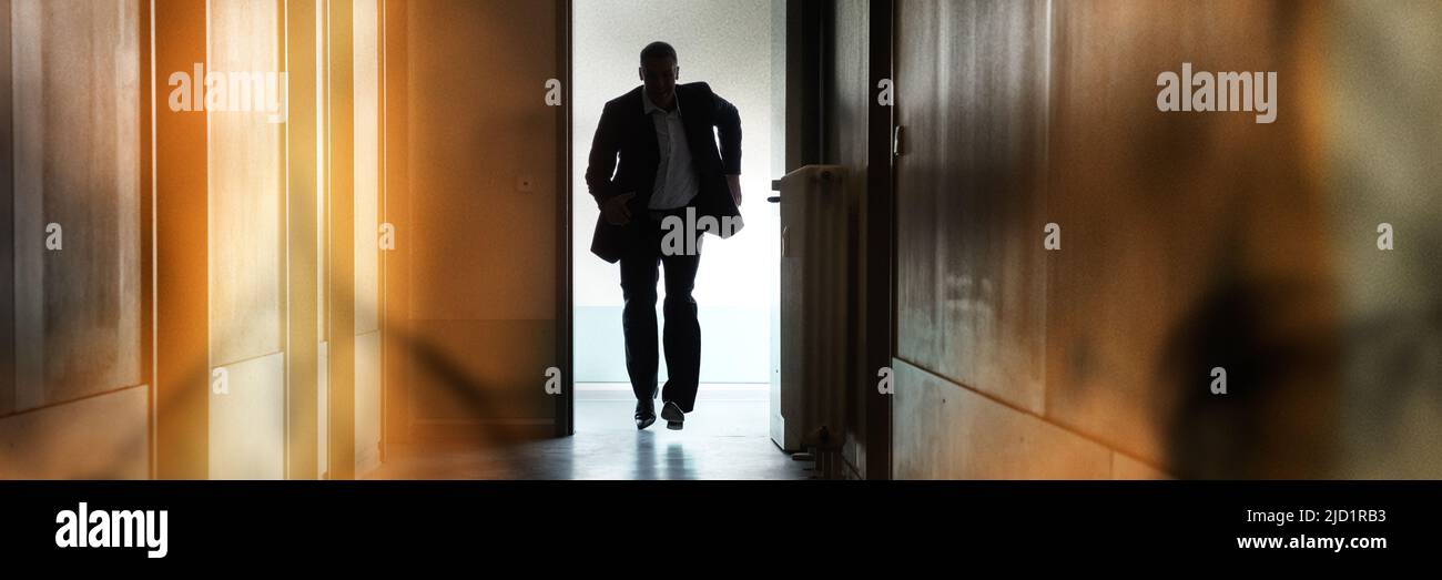 Silhouette di persona in esecuzione al di fuori della via di fuga in caso di incendi sul corridoio di costruzione Foto Stock