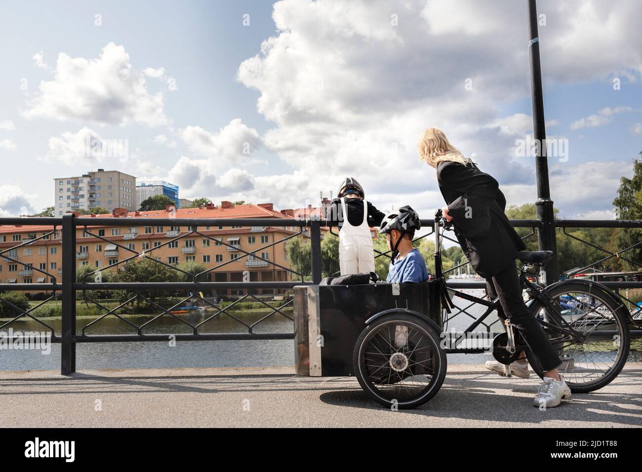 Madre in bicicletta con bambini in carrozza Foto Stock